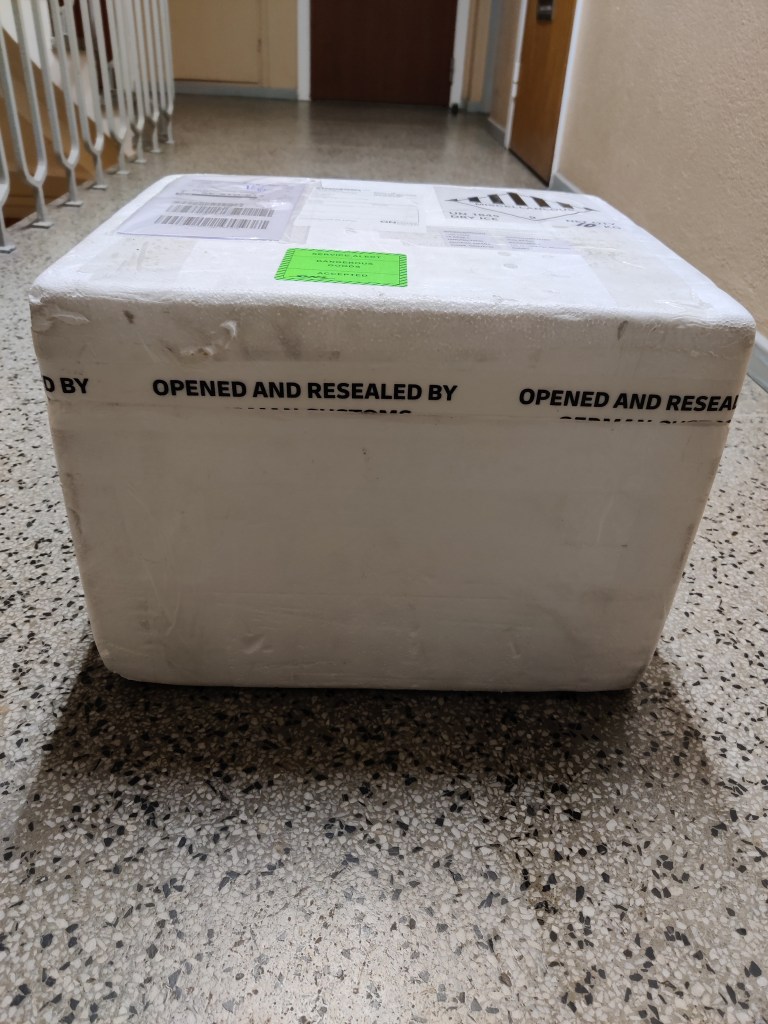 Oöppnat paket i frigolit. Innehåller 6 fryska flaskor från microbioma.org.  Kostade 18 000 kr.