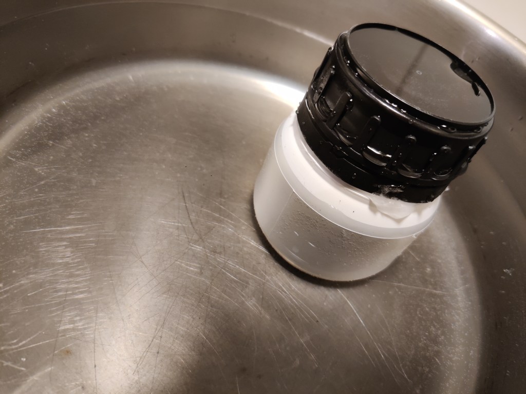 Flaska från microbioma.org med fekalt material inuti. Håller på att tinas upp i vatten. För en fekal transplantation.