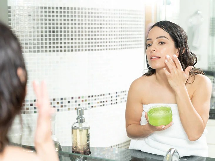 Kvinna tar aloe vera gel på ansiktet.