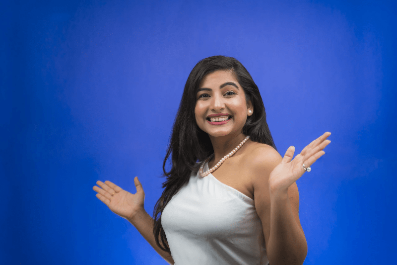 glad indisk tjej med stort leende blå bakgrund.