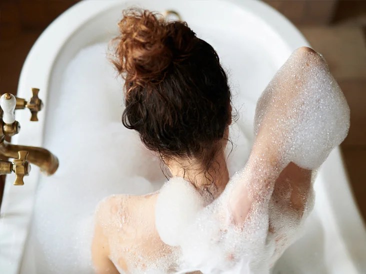 kvinna badar med massa skum.