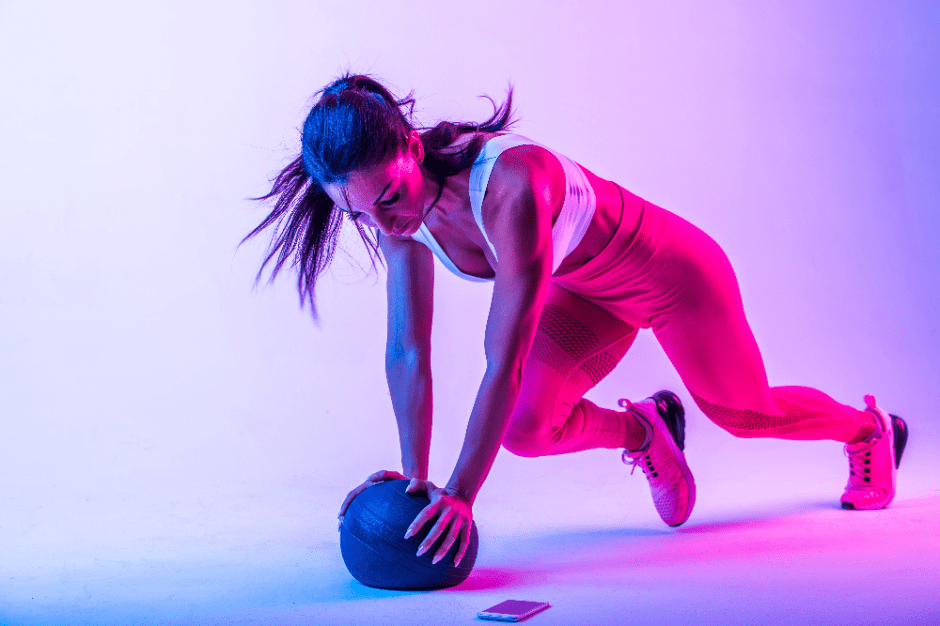 Snygg tjej tränar med en medicinboll lila bakgrund