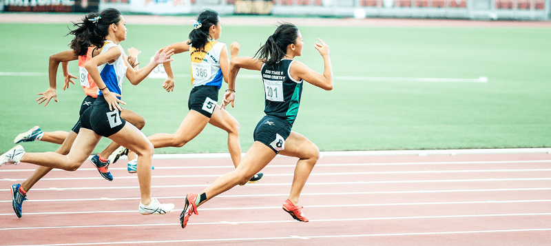 fyra kvinnliga studenter löper på en tävling löparbana.