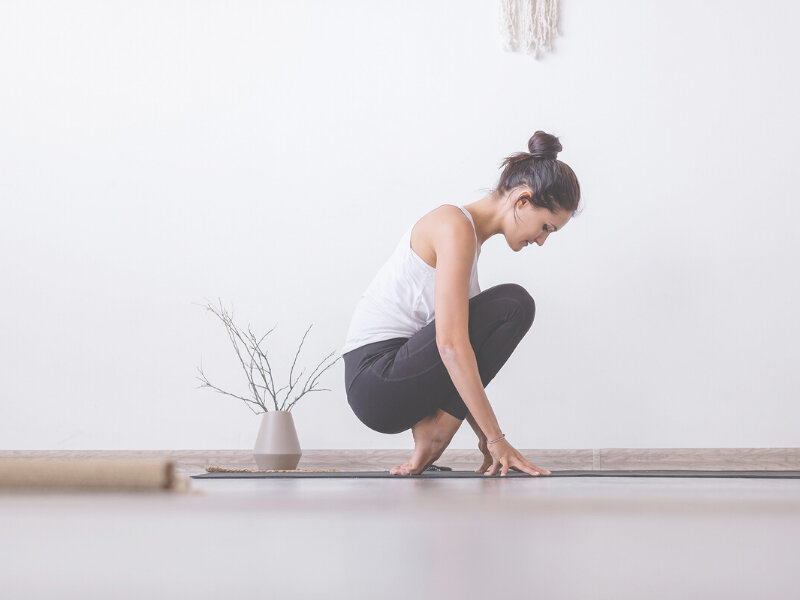 smal kvinna stretchar sina fötter på en yogamatta.