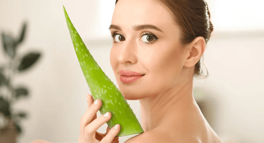 Snygg tjej med fin hud håller i ett avskuret aloe vera löv.