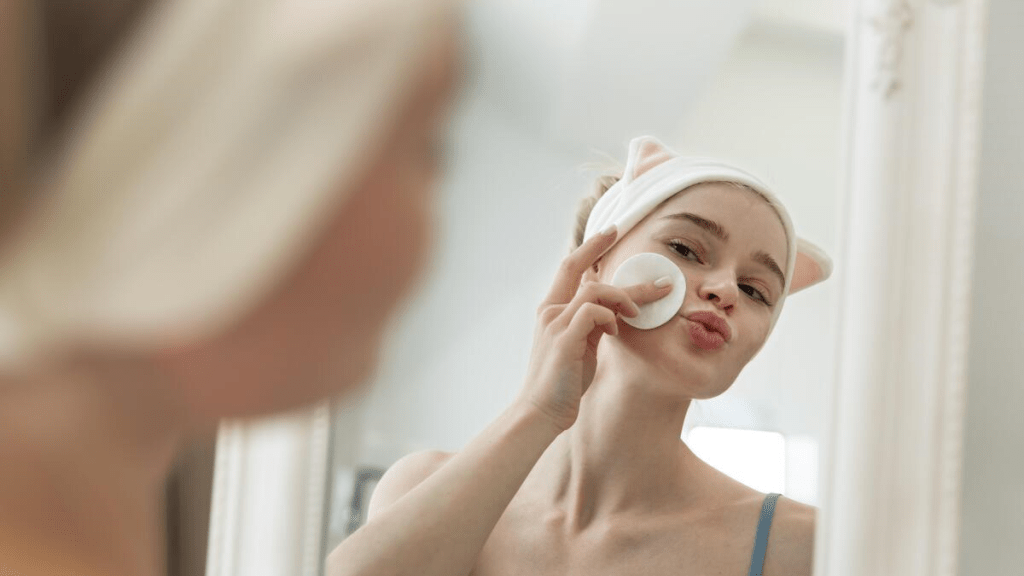 Vacker kvinna med hälsosam hud tittar sig själv i spegeln.