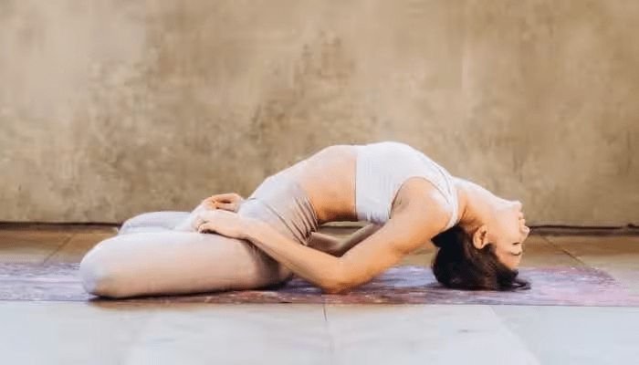 Mycket vig smal kvinna gör yoga och lutar sig bakåt.