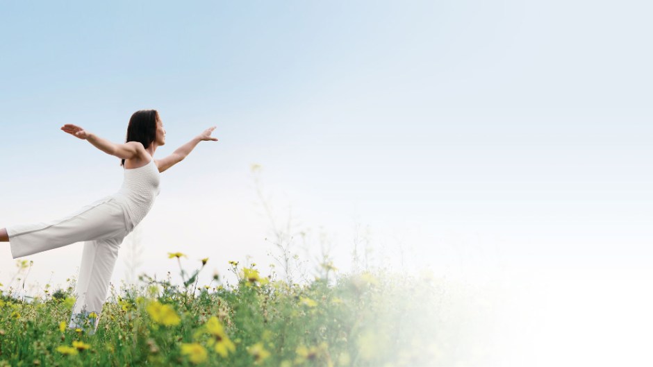 frisk smal kvinna gör yoga utonhus på en äng i vita kläder